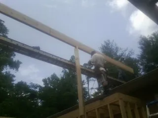 Carpenter setting a ridge beam over a new addition frame — Ice Dam Removal by Roofing Brothers in Manor