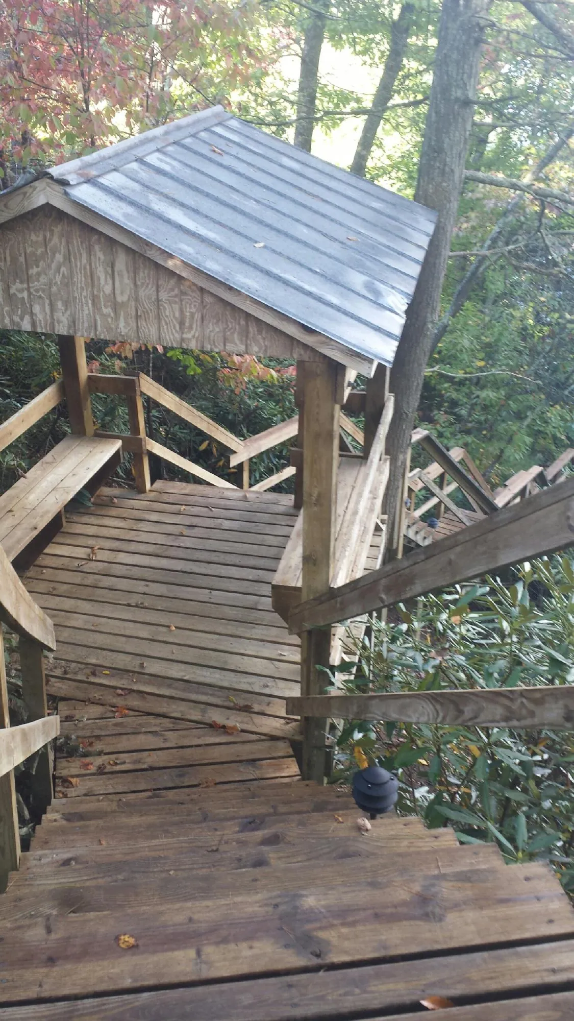 Metal roofed shelter over wooden steps on a wooded walkway — Skylight Repair & Installation work by our crew in Manor